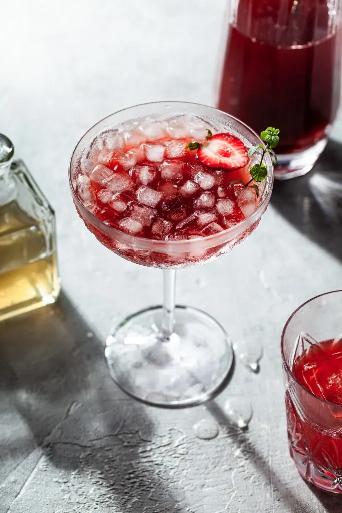 A stemmed glass filled with an iced red fruit drink.