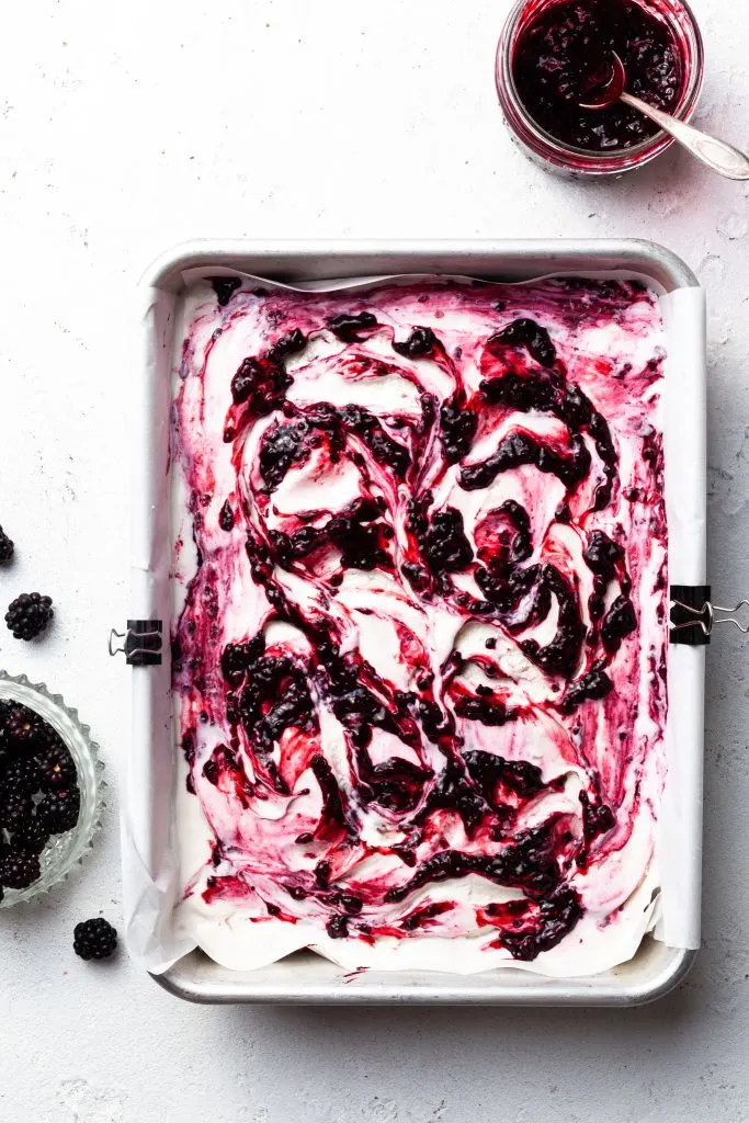 Swirls of berries through white ice cream in a parchment lined baking tin. 