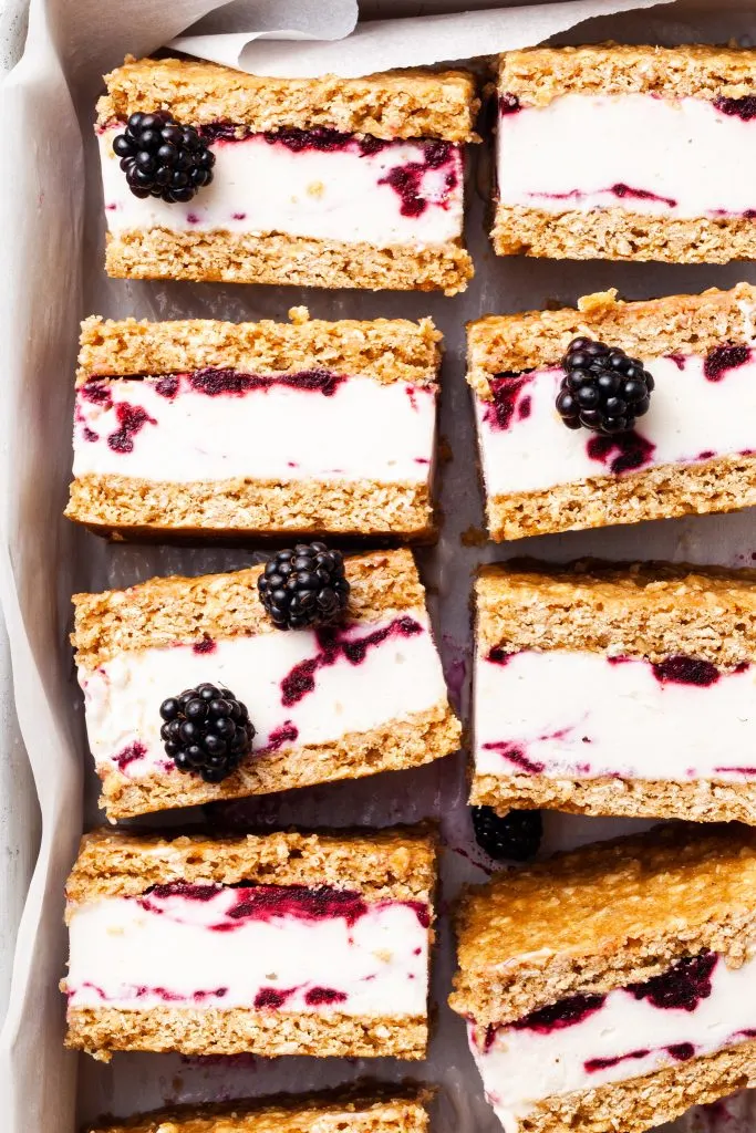 A close up shot of ice cream sandwiches on their sides, with scattered fresh blackberries. 