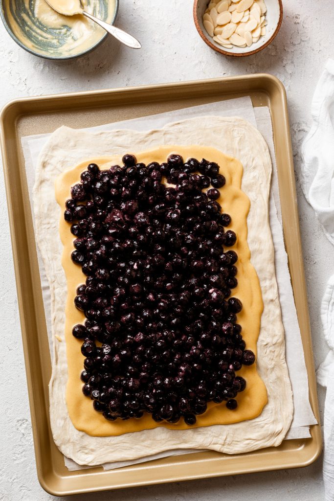 A layer of berries on top of a cream filling over pastry not yet baked. 
