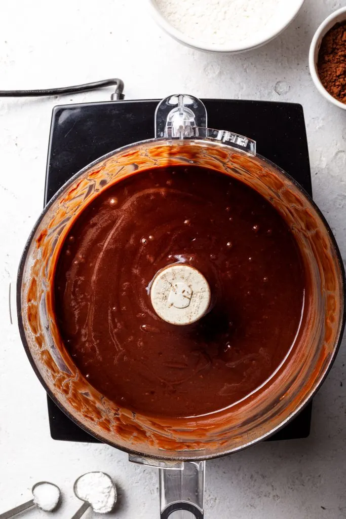 A food processor filled with a blended chocolate mixture.